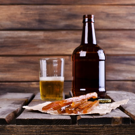 Thin sticks of smoked fish on the wooden background. Selective focus.の写真素材