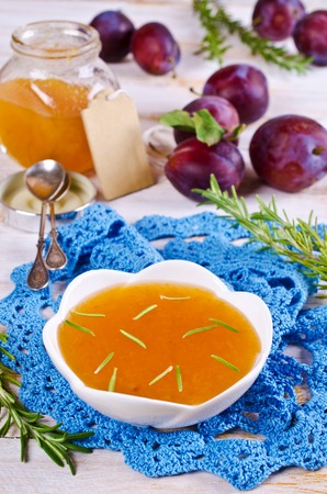 Homemade plum jam with rosemary on a wooden background. Selective focus.の写真素材
