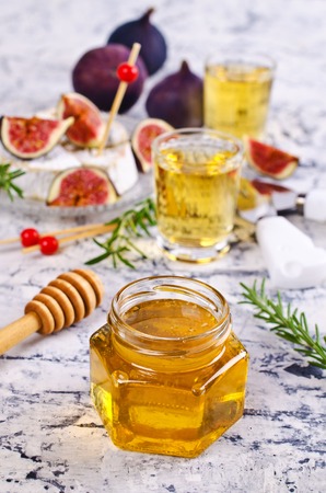 Liquid golden honey in jar on background camembert, fig and rosemary. Selective focus.の写真素材