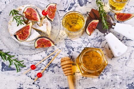 Liquid golden honey in jar on background camembert, fig and rosemary. Selective focus.の写真素材