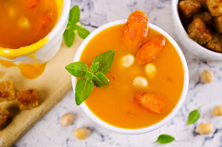Pumpkin and carrot soup with chickpeas on a light background. Selective focus.の写真素材