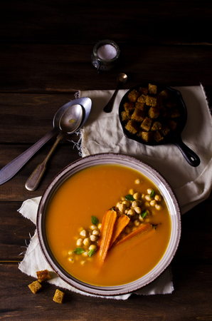Pumpkin and carrot soup with chickpeas on a dark background. Selective focus.の写真素材