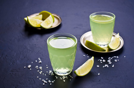 Strong drink on a dark background with salt and lime. Selective focus.
