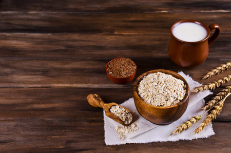 Dry oat flakes with flax seeds and milk on a dark wooden background. Selective focus.