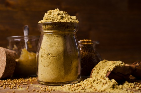 Ground mustard powder on a wooden background. Selective focus.の写真素材