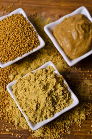Ground mustard powder on a wooden background. Selective focus.の写真素材