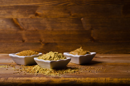 Ground mustard powder on a wooden background. Selective focus.