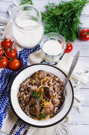 Boiled buckwheat with mushrooms and onions on a wooden background. Selective focus.の写真素材