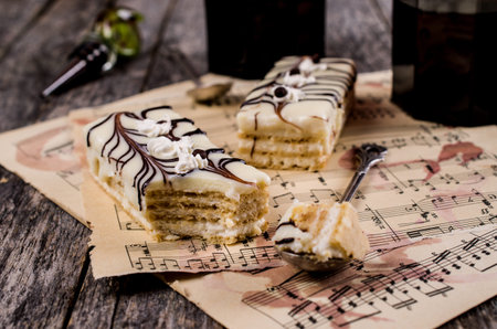 Pieces of biscuit cake with cream layers and chocolate decoration. Selective focus.