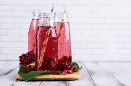 Cold transparent pomegranate drink on a wooden background. Selective focus.の写真素材