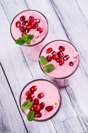 Smoothies with pomegranate seeds and mint on a wooden background. Selective focus.の写真素材
