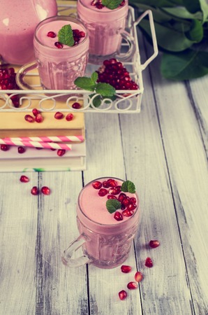 Smoothies with pomegranate seeds and mint on a wooden background. Selective focus.の写真素材