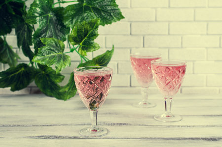 Transparent pink drink on a wooden background. Selective focus.