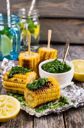 Grilled corn on sticks with green sauce. Selective focus.の写真素材