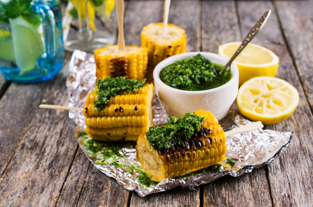 Grilled corn on sticks with green sauce. Selective focus.の写真素材