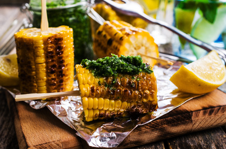 Grilled corn on sticks with green sauce. Selective focus.の写真素材