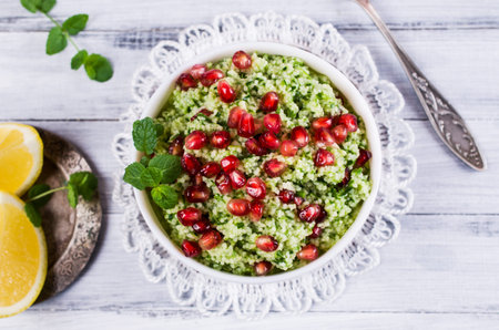Green couscous with pomegranate and mint on a wooden background. Selective focus.の写真素材