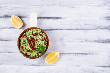 Green couscous with pomegranate and mint on a wooden background. Selective focus.の写真素材