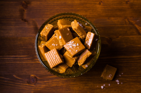 Homemade caramel candy with salt and sugar on a wooden background. Selective focus.の写真素材