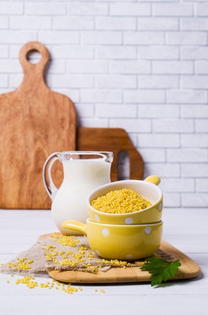 Raw organic millet and a jug of milk on a light wooden background. Selective focus.の写真素材