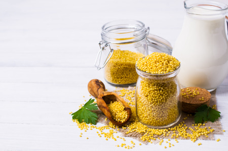 Raw organic millet and a jug of milk on a light wooden background. Selective focus.の写真素材