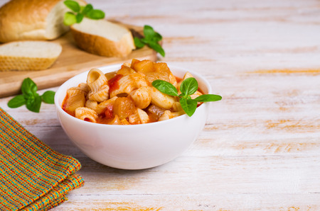 Tomato soup with pasta and vegetables on a wooden background. Selective focus.の写真素材