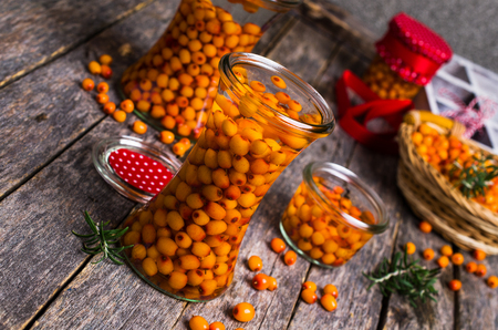 Berries of sea buckthorn with syrup in glass on a wooden background. Selective focus.の写真素材