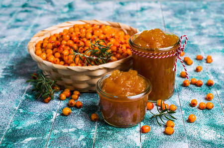 Sea buckthorn confiture in glass with berries and leaves. Selective focus.