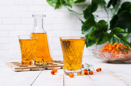 Transparent alcoholic drink from sea-buckthorn on a wooden background. Selective focus.の写真素材