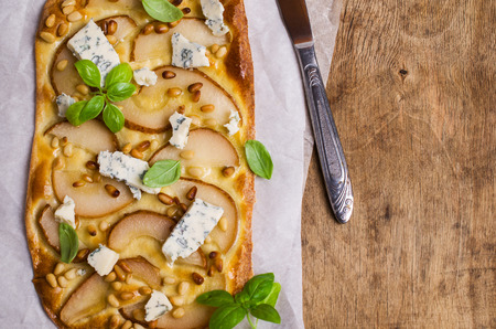 Traditional pizza with pear, nuts and blue cheese on a wooden background. Selective focus.の写真素材