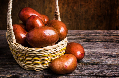 Large washed potatoes in a box on wooden background. Selective focus.の写真素材