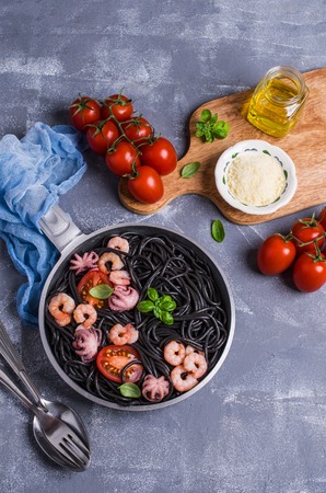 Black spaghetti with seafood and tomatoes in a plate. Selective focus.の写真素材