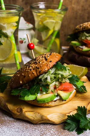 Burger with salted salmon and vegetables on wooden background. Selective focus.の写真素材