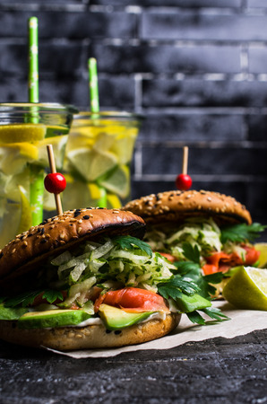 Burger with salted salmon and vegetables on wooden background. Selective focus.の写真素材