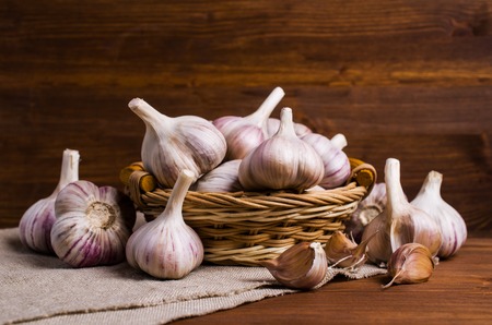 Raw garlic cloves in a box on wooden background. Selective focus.の写真素材
