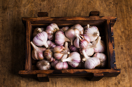 Raw garlic cloves in a box on wooden background. Selective focus.の写真素材