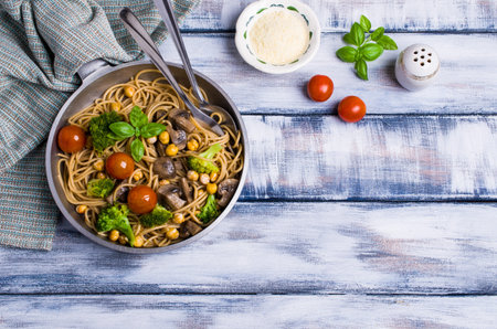Dark pasta with vegetables, mushrooms and chickpeas in a bowl on a wooden table. Selective focus.の写真素材