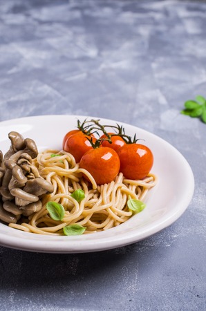 Brown paste with oyster mushrooms and tomatoes in a plate on the table. Selective focus.の写真素材