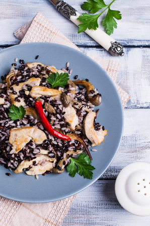Rice mix with chicken and mushrooms in a plate on a wooden background. Selective focus.の写真素材