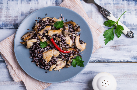Rice mix with chicken and mushrooms in a plate on a wooden background. Selective focus.の写真素材