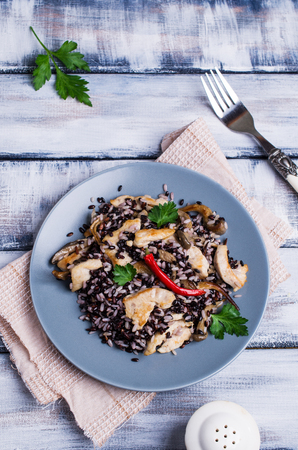 Rice mix with chicken and mushrooms in a plate on a wooden background. Selective focus.の写真素材
