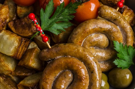 Round roast sausages with vegetables and spices on the table. Selective focus.の写真素材