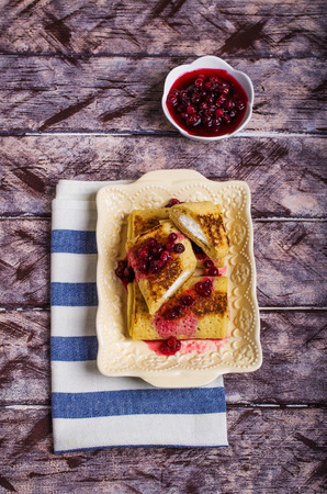 Pancakes with white filling and berry confiture in plate on wooden background. Selective focus.の写真素材
