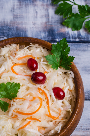 Sauerkraut with carrots and cranberries in bowl on wooden background. Selective focus.の写真素材