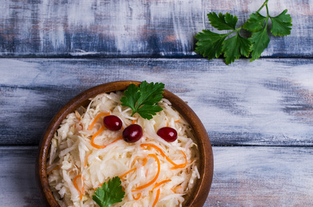 Sauerkraut with carrots and cranberries in bowl on wooden background. Selective focus.の写真素材