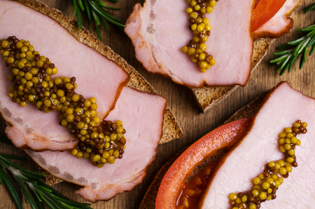 Sandwich with smoked meat and mustard on an old wooden background. Selective focus.の写真素材