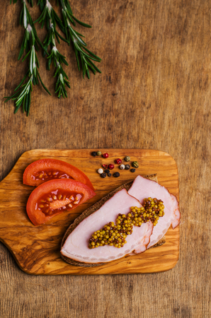 Sandwich with smoked meat and mustard on an old wooden background. Selective focus.の写真素材