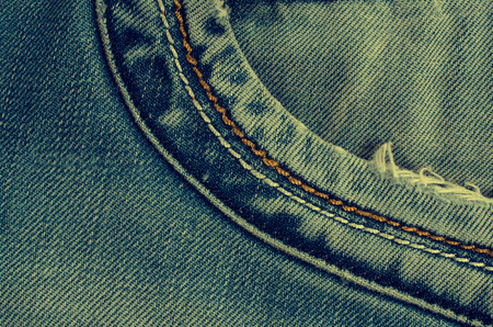 Denim texture with the effect of aging and scuffs. Grunge denim jeans fabric background. Abstract wallpaper with copy space.の写真素材