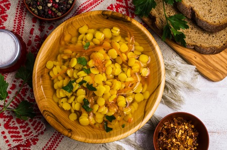 Yellow pea soup with vegetables in a plate on a wooden table. Selective focus.の写真素材