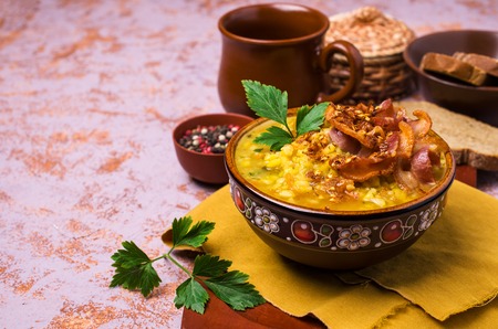 Thick pea soup with bacon and vegetables in a plate on the table. Selective focus.の写真素材